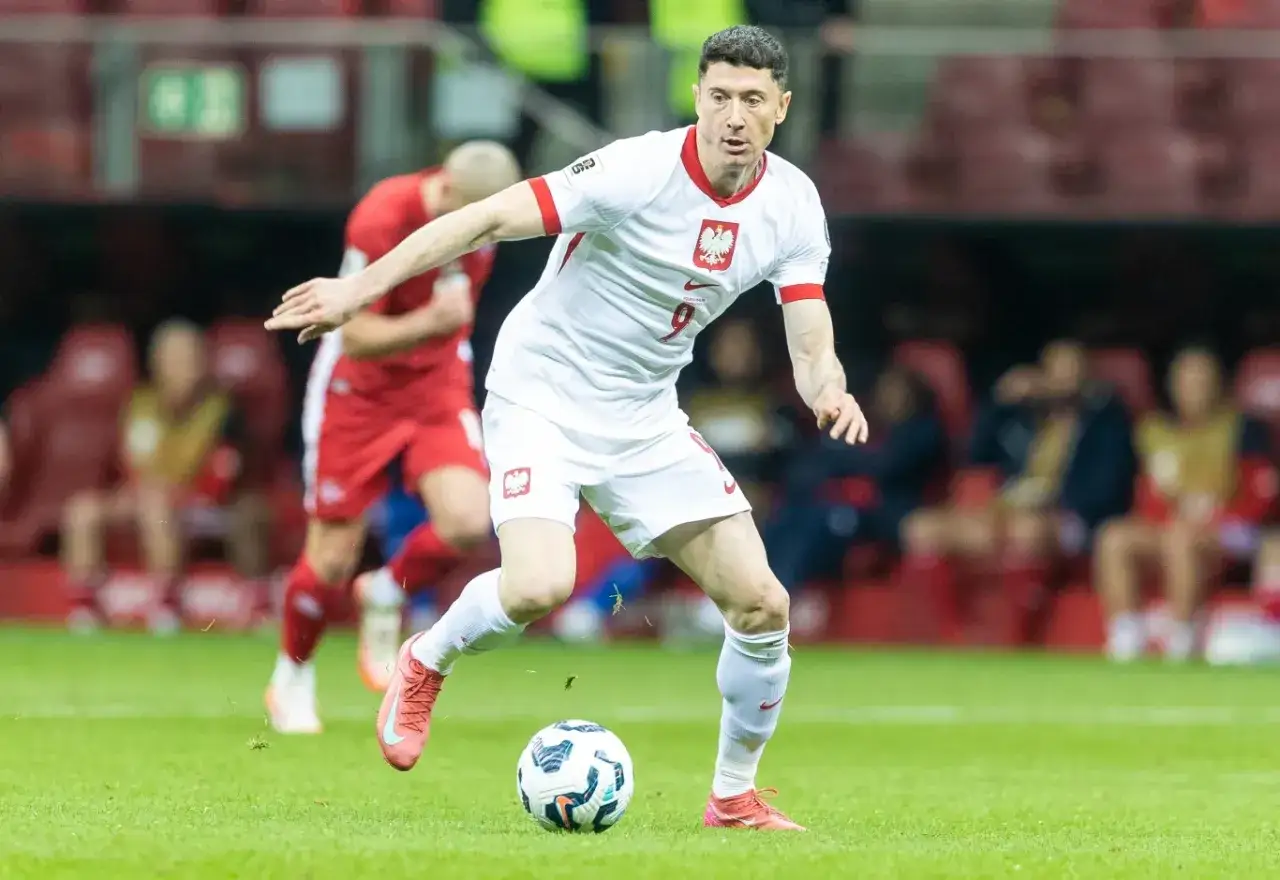 Robert Lewandowski w akcji podczas meczu, przygotowuje się do strzału. Kibice w tle czekają na kolejne emocje podczas euro meczy.