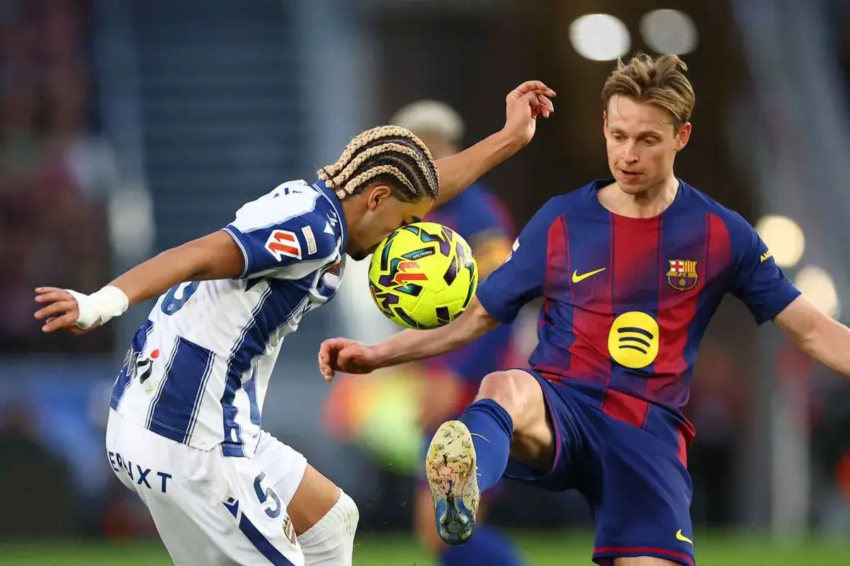 Piłkarze walczą o piłkę. Jeden z nich, Frenkie de Jong, w czerwono-niebieskim stroju, wydaje się być w trakcie akcji, która mogła doprowadzić do jego kontuzji.