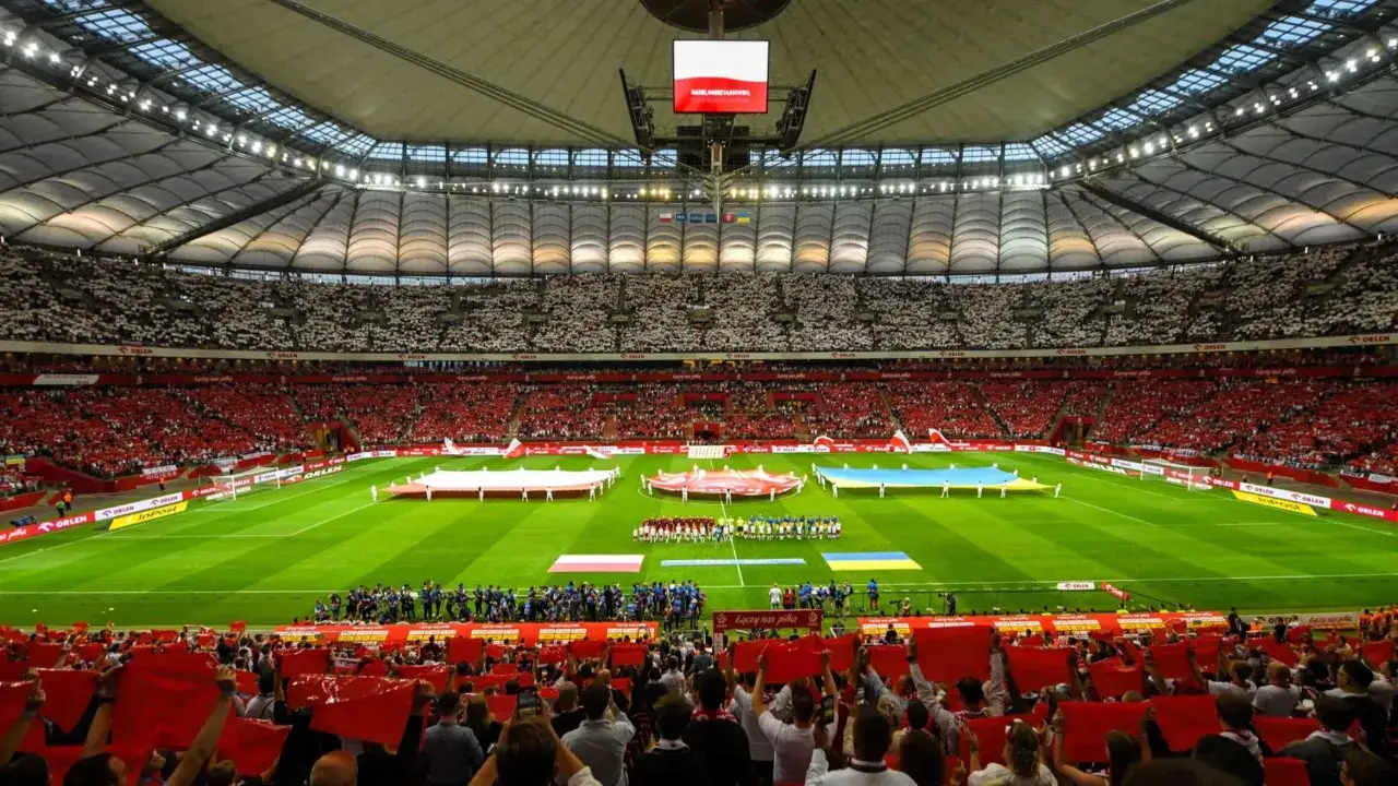 Stadion wypełniony kibicami w biało-czerwonych barwach. Na murawie flagi Polski i Ukrainy. Rozgrywki i liga w pełnym blasku.
