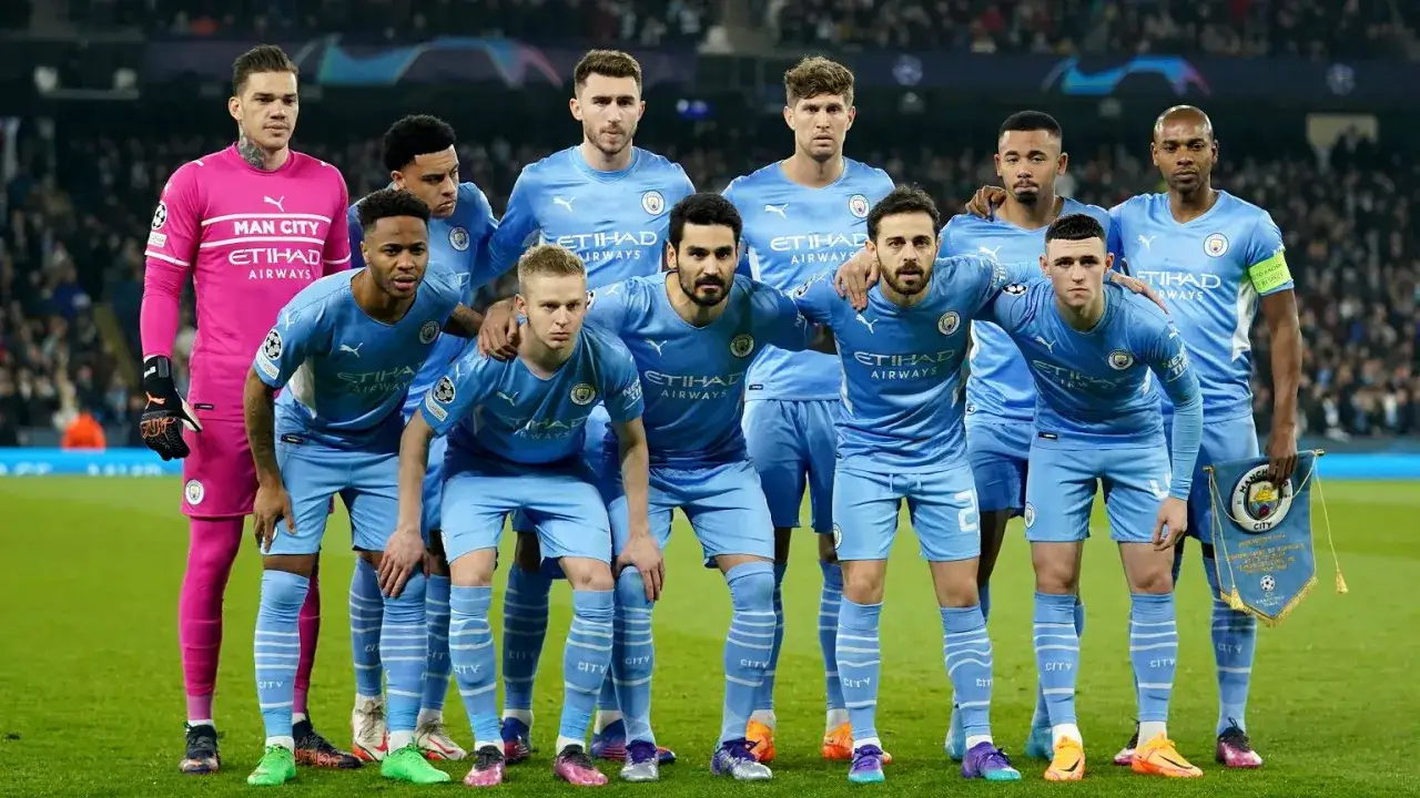 Piłkarze Manchesteru City w jasnoniebieskich strojach pozują do zdjęcia przed meczem. W bramkarskim różowym stroju stoi Ederson.
