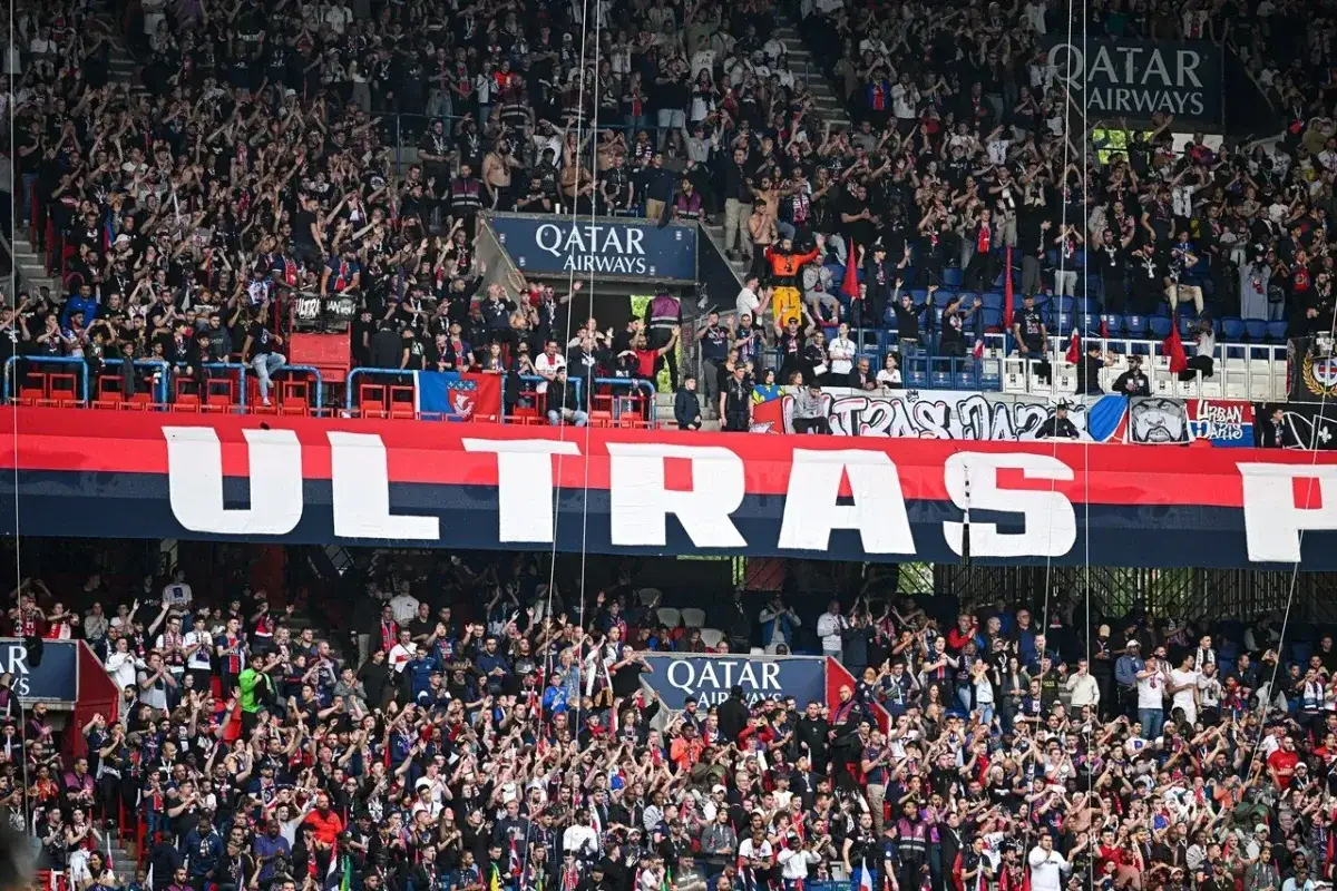 Tłum kibic&oacute;w na stadionie, dopingujący swoją drużynę podczas meczu ligi francuskiej. Na trybunach rozwinięty ogromny transparent z napisem 