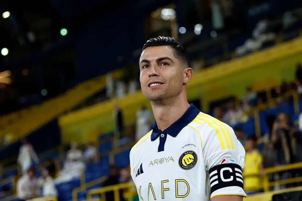 Cristiano Ronaldo w koszulce Al Nassr, z opaską kapitana na ramieniu, na tle trybun stadionu.