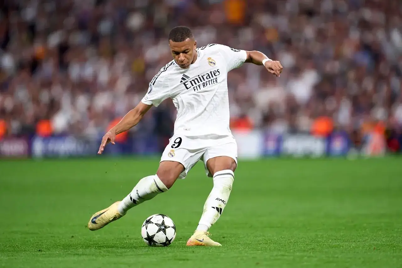 Piłkarz Real Madryt w białej koszulce z numerem 9 drybluje piłkę. Mecz z AC Milan.