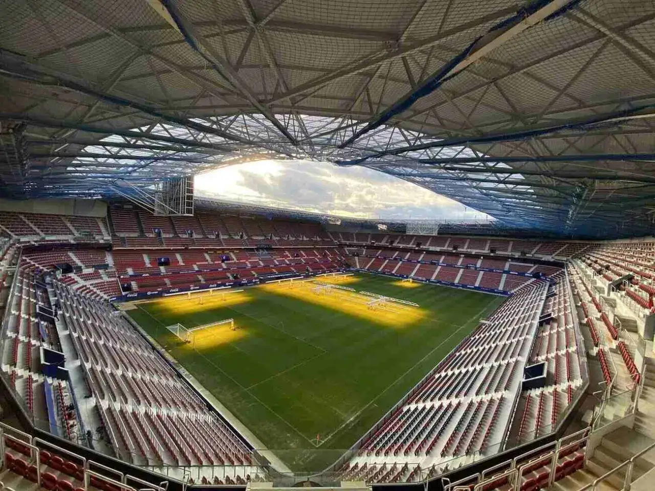 Puste trybuny stadionu El Sadar, domu Osasuna FC, czekają na kibiców. Słońce oświetla zieloną murawę.