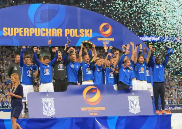 Piłkarze świętują zdobycie Superpucharu Polski, unosząc trofeum i ciesząc się deszczem konfetti.