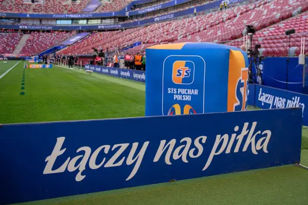Stadion przed meczem STS Puchar Polski. Na zielonej murawie i trybunach widać logotypy i hasło "Łączy nas piłka".