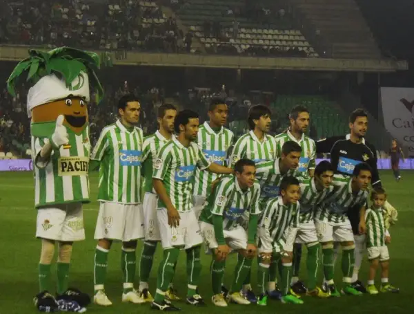 Drużyna Real Betis – zawodnicy w zielono-białych strojach pozują do zdjęcia z maskotką.