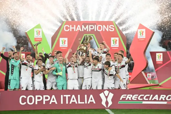 Bologna FC świętuje zwycięstwo w rozgrywkach Coppa Italia, wznosząc puchar na tle fajerwerków i napisu "CHAMPIONS".