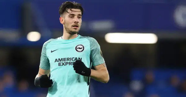 Piłkarz Jakub Moder w turkusowej koszulce Brighton & Hove Albion, z rękawiczkami na dłoniach, gotowy do gry.