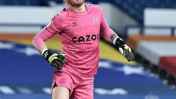Jordan Pickford, bramkarz Anglii, w różowym stroju Evertonu, gotowy do obrony.