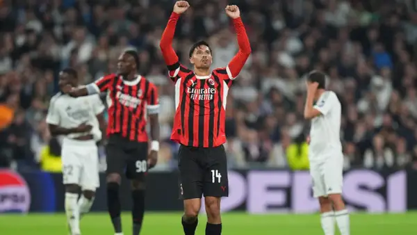 Piłkarz AC Milan z podniesionymi rękami świętuje zwycięstwo nad Realem Madryt.