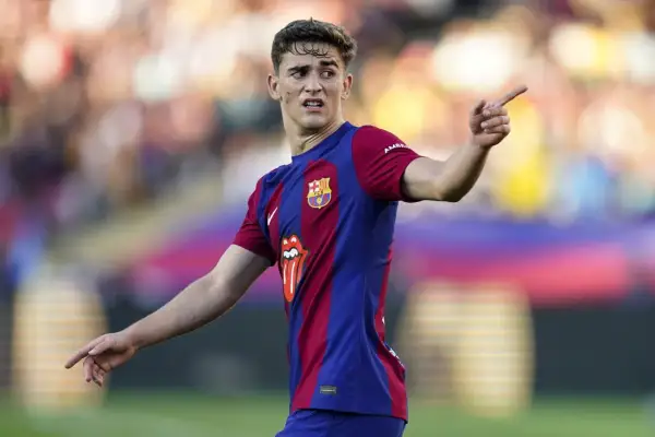 Młody gavi pilkarz FC Barcelony w akcji, z wyrazem skupienia na twarzy i uniesionym palcem wskazującym.