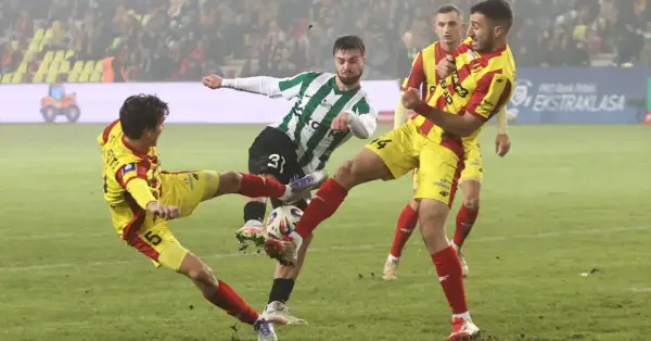 Zacięta walka o piłkę w meczu Korona Kielce – Zagłębie Lubin. Piłkarze w żółto-czerwonych strojach walczą z zawodnikiem w zielono-białej koszulce.