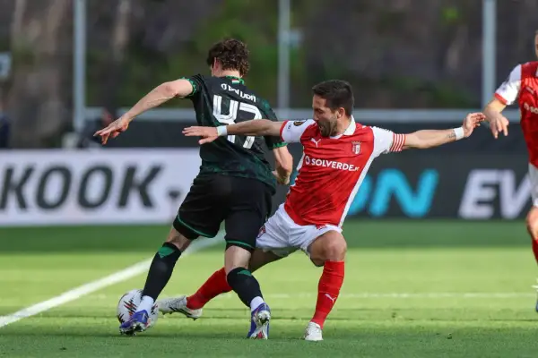 Piłkarze w akcji podczas rozgrywek SC Braga. Jeden w czerwonej koszulce, drugi w zielonej.